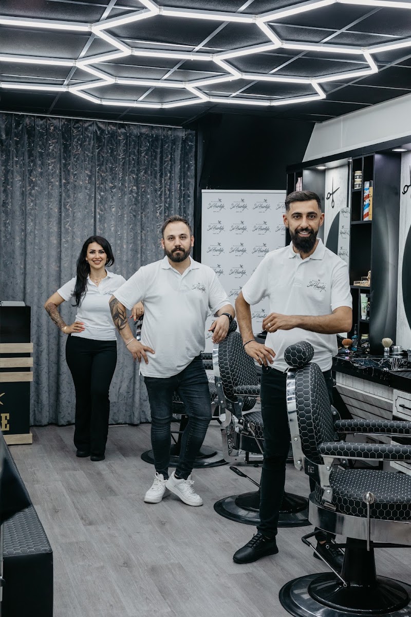Drie kappers van Siv Hairstyle in de salon, in witte poloshirts met het logo erop.